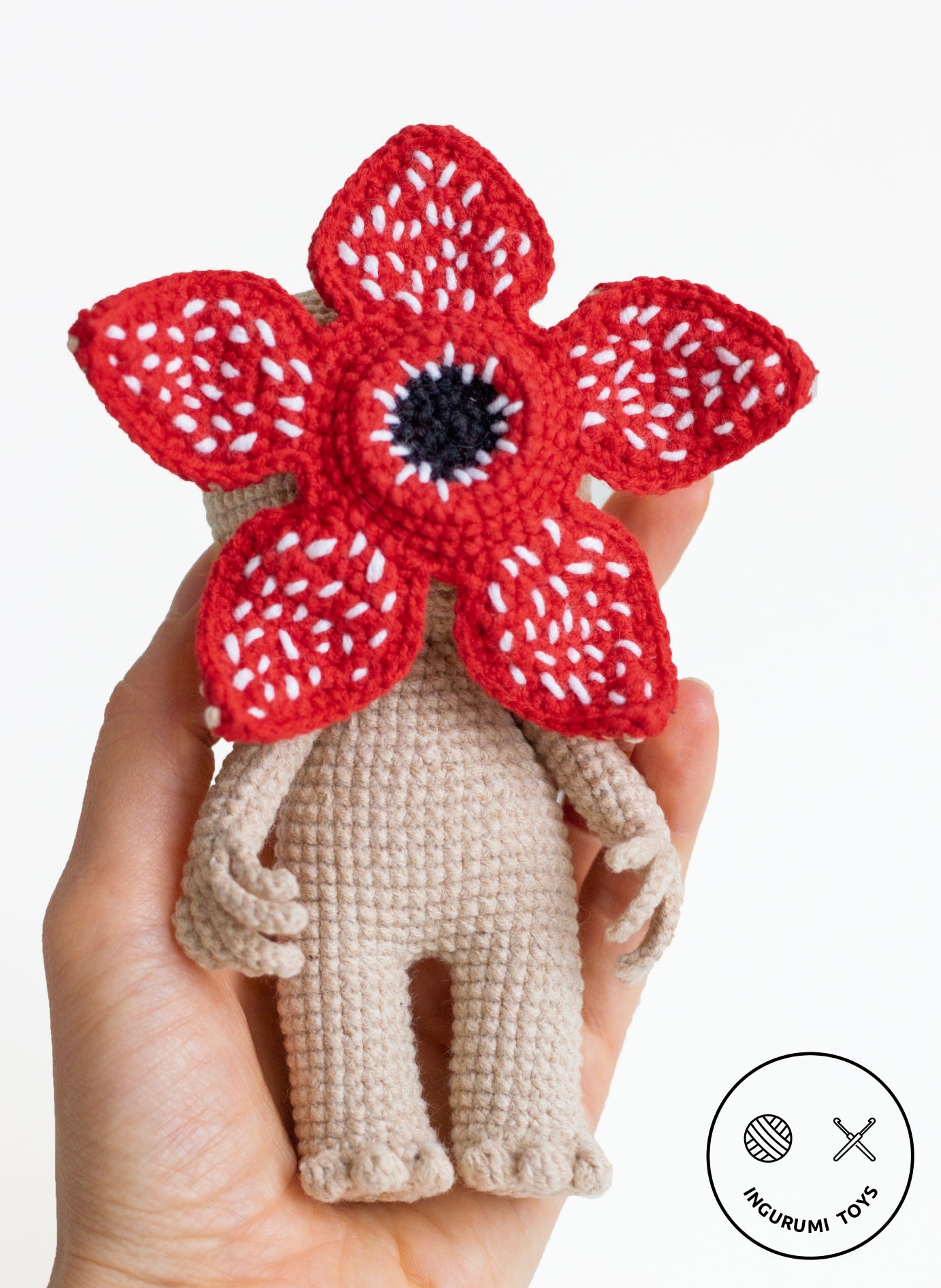 Hand holding a small handmade Demogorgon amigurumi toy showing scale and detailed stitching.