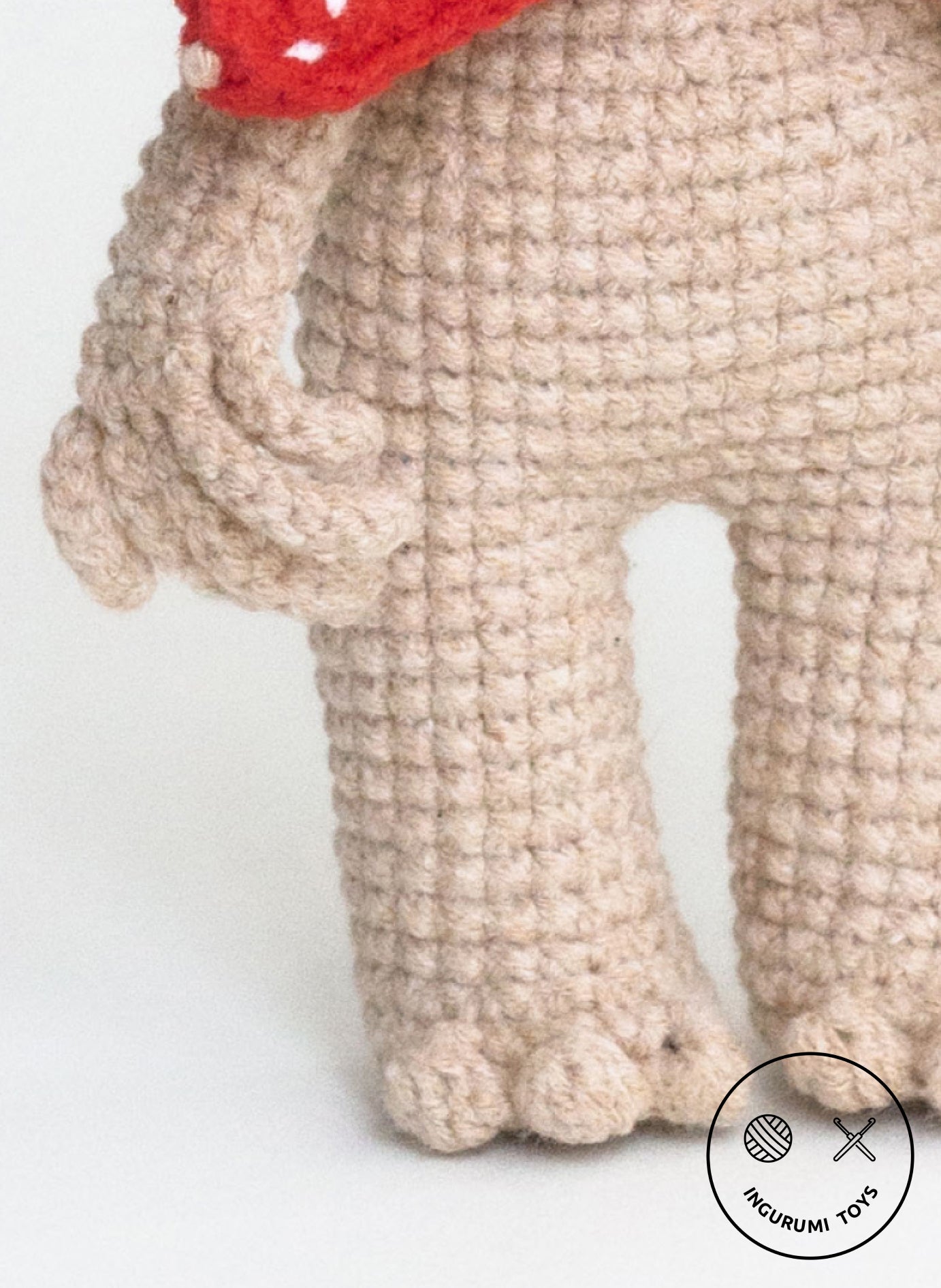 Crochet texture of a handmade monster amigurumi body with visible small arms and fingers in beige yarn.
