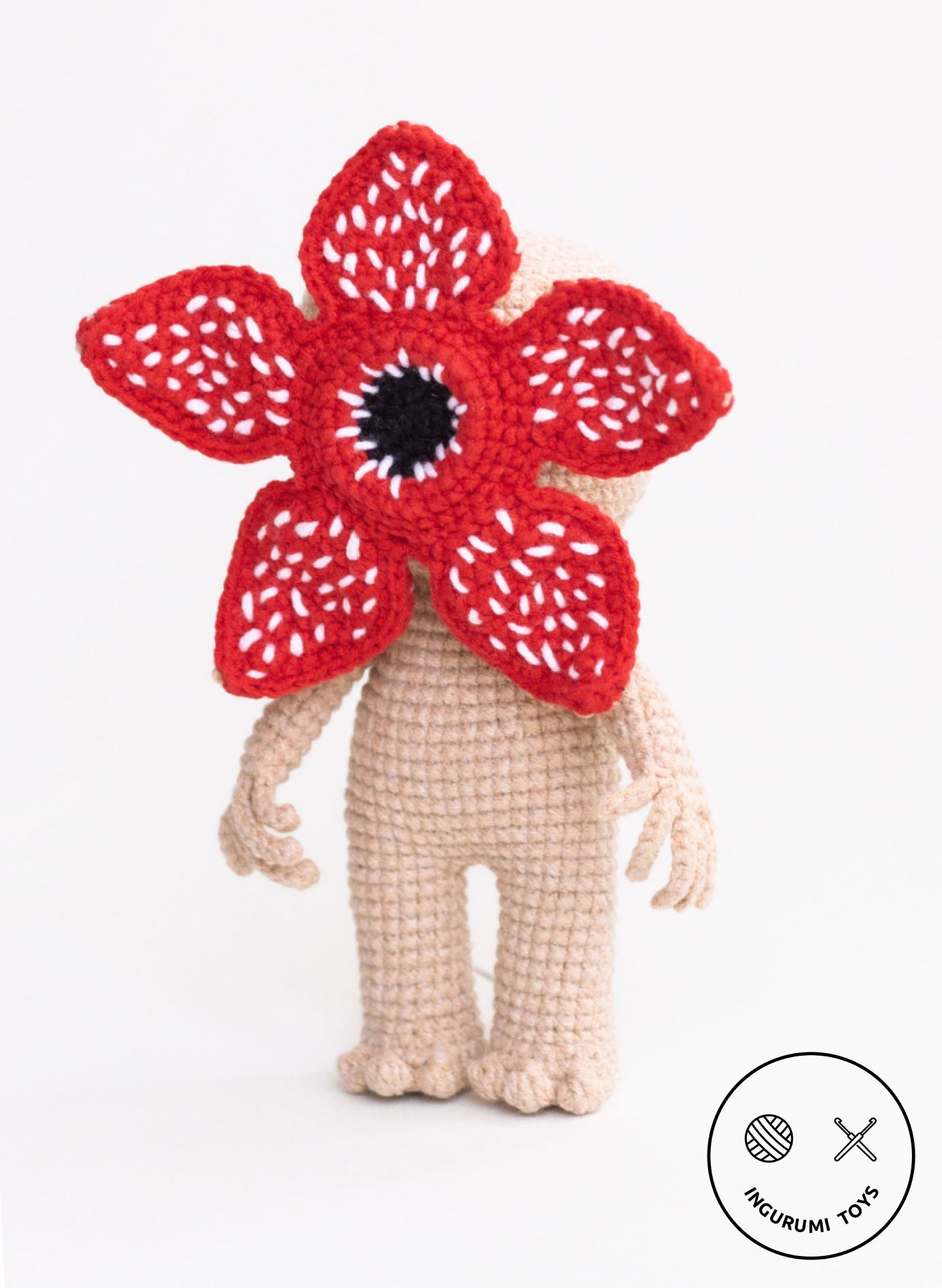 Standing crocheted Demogorgon amigurumi doll with red petals and black center detail.